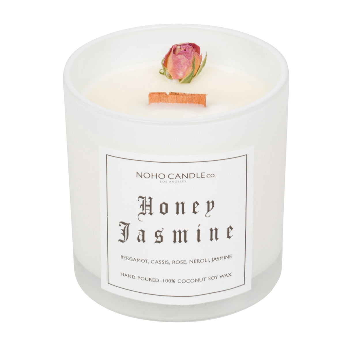 A 10oz Wood Wick Honey Jasmine Floral Collection candle.  The wax is white and there is a single dried, natural rose positioned near the edge.  The candle has been poured into a white translucent glass that comes with a clear, translucent lid.