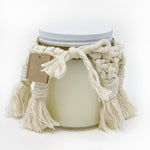 Unlit candle with a macrame cover and a gift tag on it.