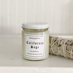 A California Sage candle next to a bundle of sage.