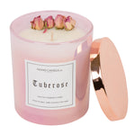 A 14oz Tuberose cotton wick candle from the floral collection.  The wax is white and there are four natural, dried roses arranged around the outer edge.  The candle is poured into an iridescent pink glass with a copper lid that pops on and off.